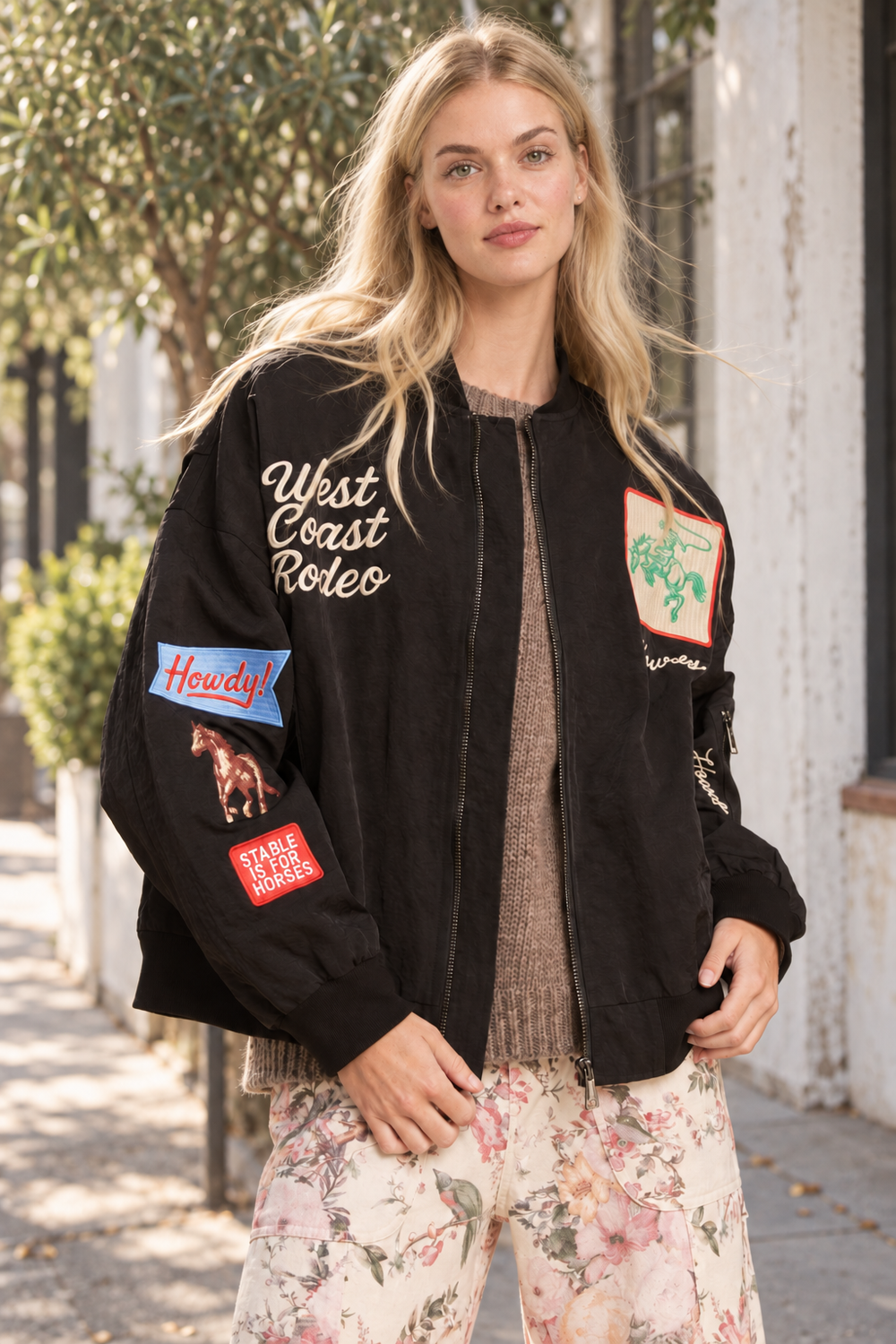 Carter black embroidered bomber jacket styled over a taupe knit in natural outdoor light.