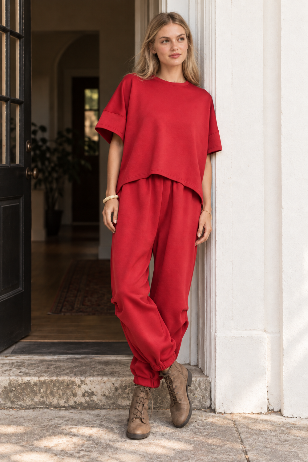 Solace red dolman lounge set shown as a complete outfit in a relaxed doorway pose.
